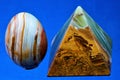 Onyx is a valuable and extremely beautiful mineral, pyramid and egg on a blue background.