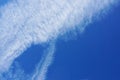 Distorted clouds on a intense blue sky. Plane trace Royalty Free Stock Photo