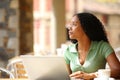 Distracted black woman with laptop looking away in a restautant