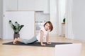 Distracted nine year old girl trying to do a plank on a mat at home. Royalty Free Stock Photo