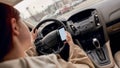 Distracted young female driver looking at the screen of her mobile phone while driving a car. Technology and Royalty Free Stock Photo