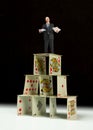 Distraught man in business suit standing on house of cards
