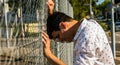 Distraught Man Pushing Head Against Fence Royalty Free Stock Photo