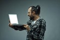 Distraught man staring at his handheld laptop screen in horror Royalty Free Stock Photo