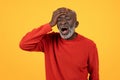 Distraught senior Black man with a white beard holding his head in his hand