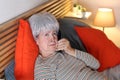 Distraught senior woman calling from bed