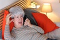 Distraught senior woman calling from bed