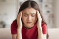 Distraught young asian woman with painful face expression holding her temples Royalty Free Stock Photo