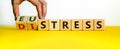 Distress or eustress. Male hand turns cubes and changes the word `distress` to `eustress`. Beautiful yellow table, white