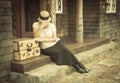 Distressed 1920s Girl Near Suitcases on Porch with Vintage Effect Royalty Free Stock Photo