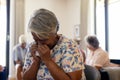 Distressed senior biracial woman holding tissue and crying in group therapy session