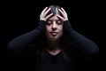 Distressed, woman holding the head with the hands, on a black or dark background Royalty Free Stock Photo