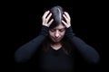 Distressed, woman holding the head with the hands, on a black or dark background Royalty Free Stock Photo