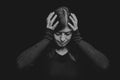 Distressed, woman holding the head with the hands, on a black or dark background Royalty Free Stock Photo