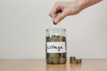 Distribution of cash savings concept. Hand puts coins to the glass money boxes with inscription `college`. Royalty Free Stock Photo