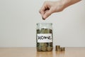 Distribution of cash savings concept. Hand puts coins to the glass money boxes with inscription `home` Royalty Free Stock Photo