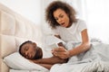 Distrustful black woman checks her boyfriend& x27;s cellphone in modern bedroom Royalty Free Stock Photo