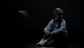 Distrustful little girl sitting in dark room refusing adult helping hand, fear