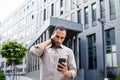 Disturbed arab man rubbing head with hand while looking at mobile phone screen on background of office building Royalty Free Stock Photo