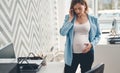 Disturbed pregnant lady talking on cellphone in office Royalty Free Stock Photo