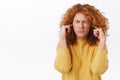 Disturbed timid cute redhead curly woman hate hear someone shouting, squinting, close eyes and purse lips from