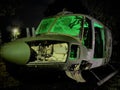 Disused abandoned Helicopter grounded at night with green lighting to show nose body component parts and lit windows