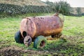 A disused, delapidated slurry tanker sits abandoned in a muddy field