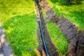 A ditch dug in the lawn for laying pipes and installing irrigation. Soil under green lawn and grass root system