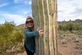 Ditzy blonde woman gives a Saguaro cactus a hug