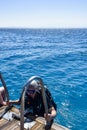 Diver after diving. Diving lesson in open water. Man with scuba diving after diving into deep sea climbs onto yacht. Royalty Free Stock Photo