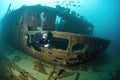 diver exploring the wreck of a sunken ship, with fish swimming in schools among the wreckage