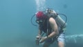 A diver lifts a rock in the sea