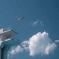 Diver in Mid-Air Above Towering Platform Against Blue Sky Royalty Free Stock Photo