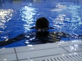 A diver in a neoprene wetsuit trains in the pool. A conrol of inexperienced divers