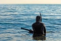 Scuba diver with spear gun ready to go underwater and spearfishing - sea landscape at sunset