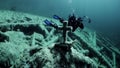 Diver videographer near grave with cross underwaterin Fernsteinsee lake Tyrol.