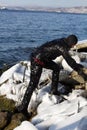 Diver working in difficult Arctic conditions. diver in black dry suit climbs on icy stones,