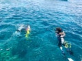 Divers in black diving waterproof suits with shiny metal aluminum canisters float, dive into the blue sea water on vacation, a sea Royalty Free Stock Photo