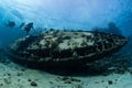 divers visiting an underwater wreck of a metal sailboat