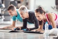 Diverse age group doing elbow planks on mats inside the gym with a plastic water bottle in the front Royalty Free Stock Photo