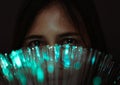 Diverse Asian girl looks through futuristic teal coloured bokeh - Millennial woman looking at camera with advanced fibre