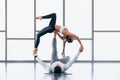 Athletic couple practicing acro yoga or yoga partner together in gym