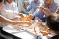 Diverse workers taking pizza from box on table eating together Royalty Free Stock Photo