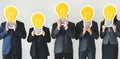 Diverse business people holding lightbulb icons over faces Royalty Free Stock Photo