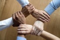 Diverse business people team grasping hands, close up top view