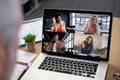 Diverse business people waving displayed on laptop screen during office video call