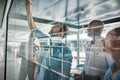 Diverse businesspeople brainstorming on a glass wall in an offic Royalty Free Stock Photo