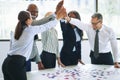 Diverse businesspeople high fiving while solving a jigsaw puzzle