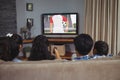 Diverse children watching tv with football match on screen