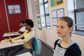 Diverse classmates sitting at desks in classroom using pencils, typing on laptop, copy space Royalty Free Stock Photo